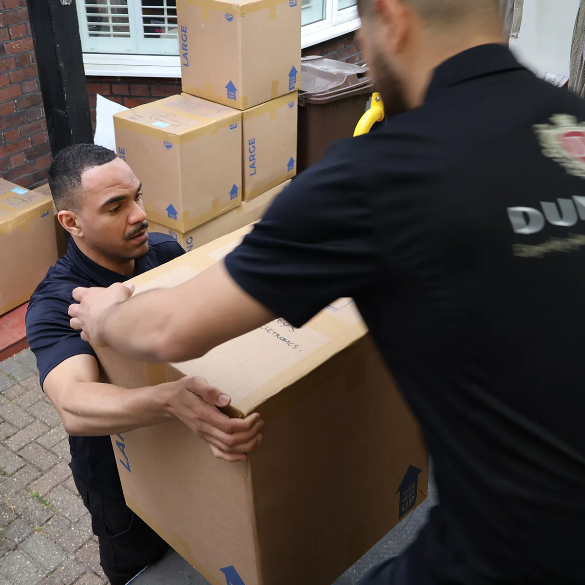 Two Dumond employees carrying moving boxes during a relocation.