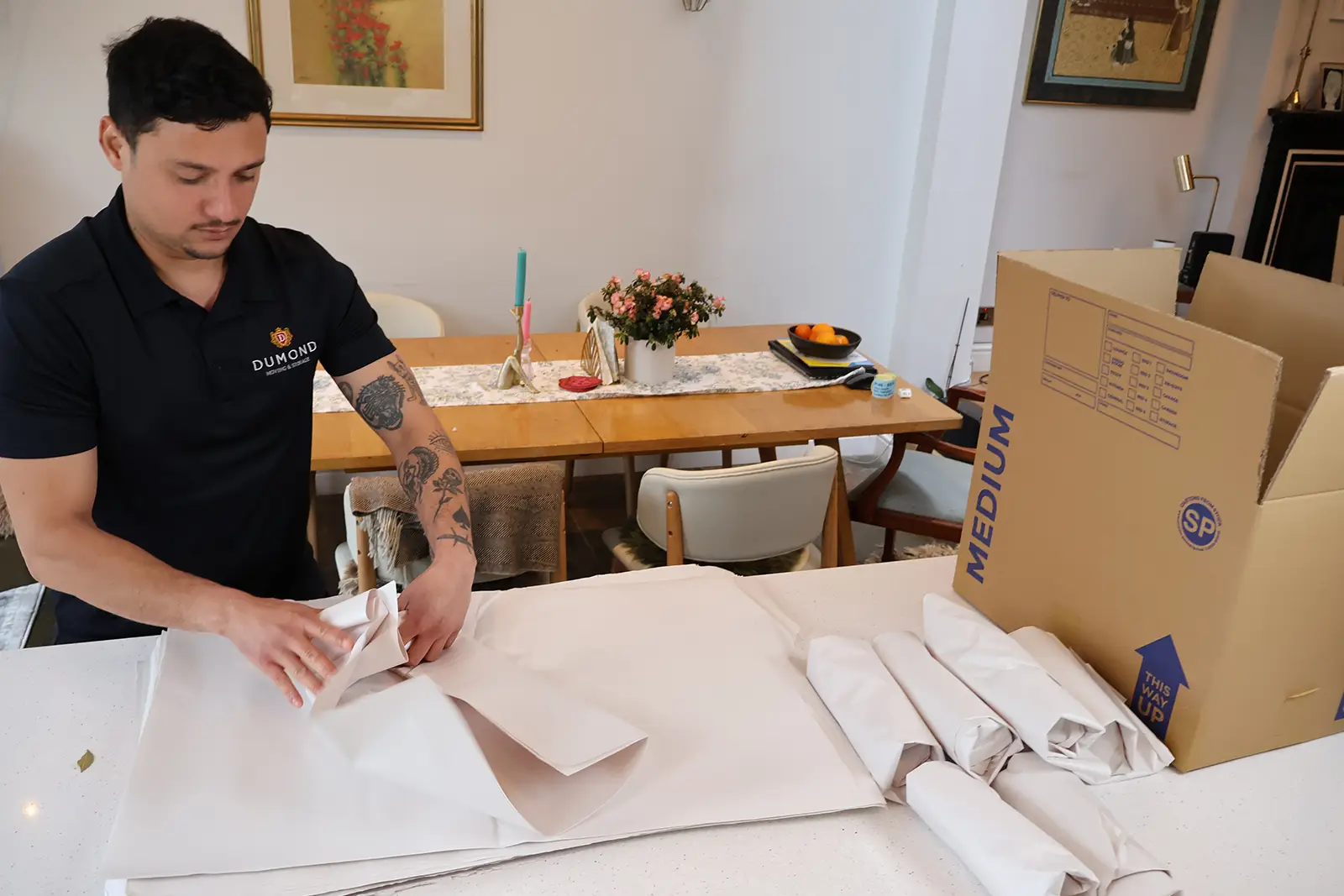 Careful packing of delicate household items using protective wrapping paper during a home move.