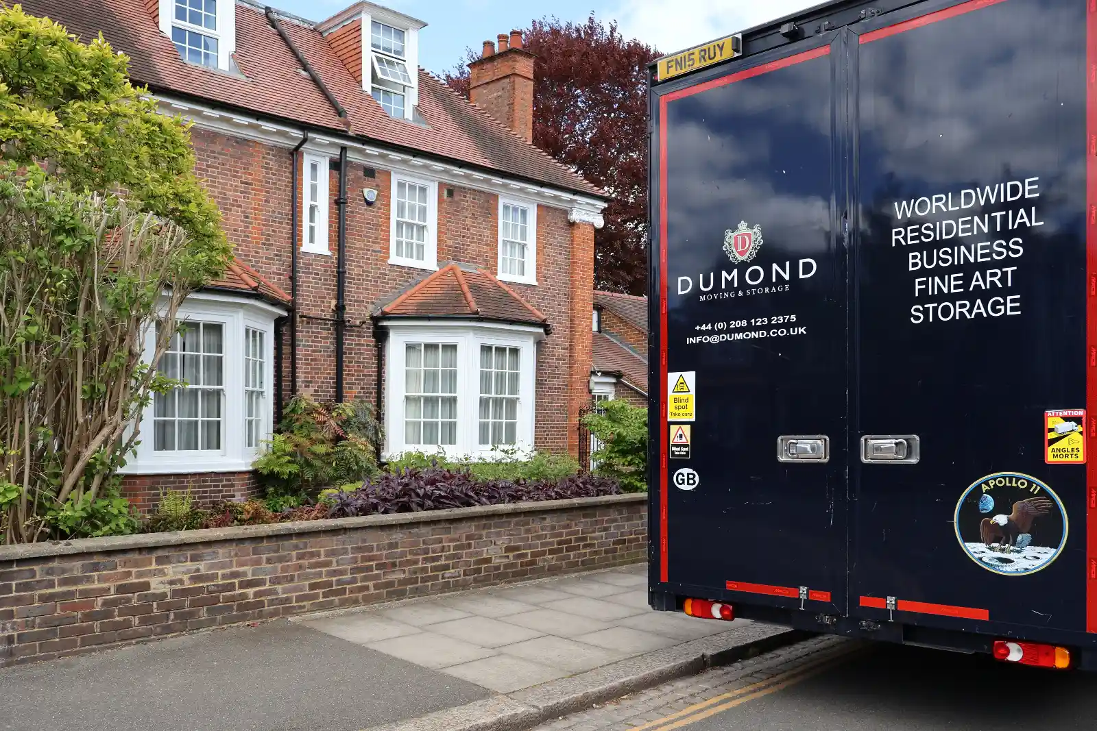 Rear view of a Dumond removals van outside a residential property representing a trusted UK moving partner.